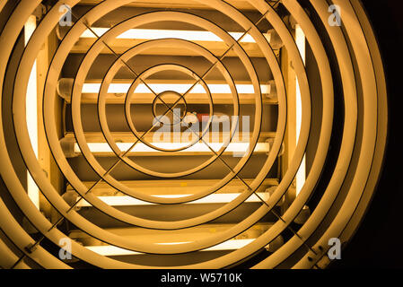 An old light bulb in the middle of fluorescent tubes Stock Photo