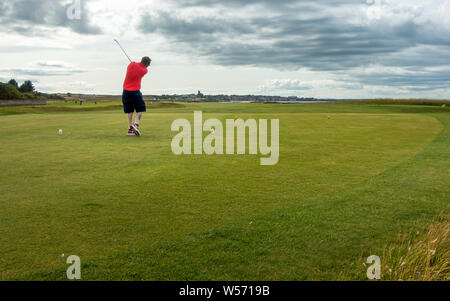 Person teeing off on Dunbar Golf Course with views over Dunbar, East Lothian, Scotland Stock Photo