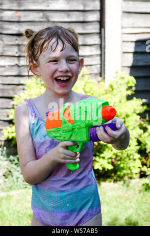 Preteen caucasian girl playing wth a water gun on a hot summer's day Stock Photo