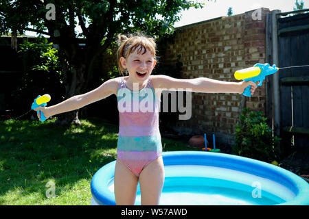 Preteen caucasian girl playing wth water guns on a hot summer's day Stock Photo