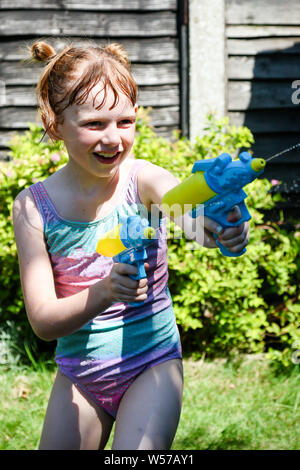 Preteen caucasian girl playing wth water guns on a hot summer's day Stock Photo