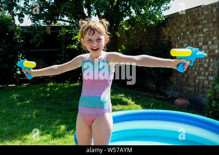 Preteen caucasian girl playing wth water guns on a hot summer's day Stock Photo