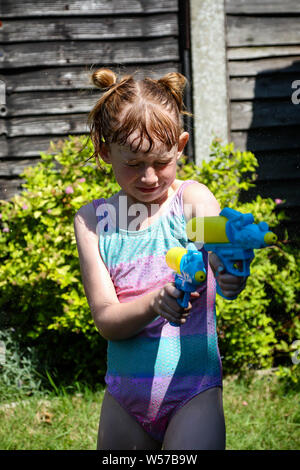 Preteen caucasian girl playing wth water guns on a hot summer's day Stock Photo