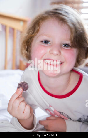 Young girl smiling to reveal a missing front tooth / teeth tooth, whilst holding a 50p / fifty  pence coin in which arrived from the tooth fairy under her pillow. UK (111) Stock Photo