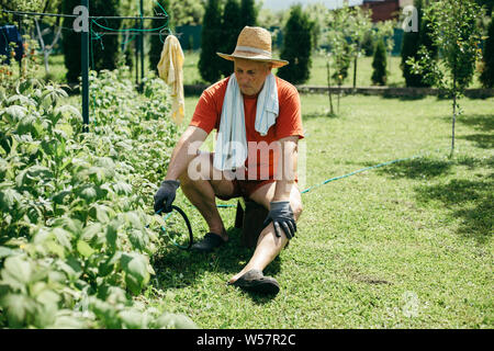 A man sitting on the chair and watering garden Stock Photo