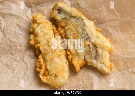 Two fillets of mackerel, Scomber scombrus, that have been dipped in flour and batter and deep fried to go in a homemade mackerel burger. The mackerel Stock Photo