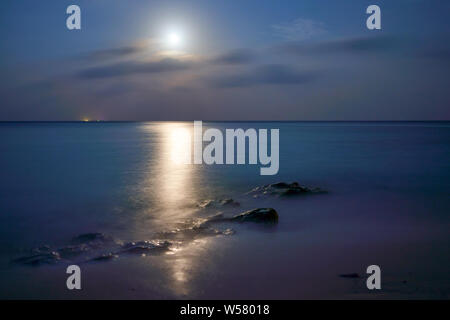 Beautiful sunset, Dark with the moon shinning on the smooth surface of the sea and rocks in Kandolhu island Maldives 2019 Stock Photo