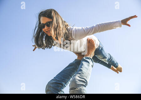 I believe i can fly, low angle view of image with one parent, strong father supports his excited daughter making plane yelling having a lot of safety, Stock Photo