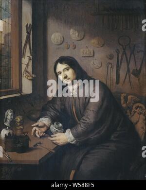 Portrait of a Goldsmith, Portrait of a goldsmith, sitting in his workshop at a work table, holding a silver jug. On the table is a floating hammer, other tools and two cobblestones. On the wall a scale, plaques, pliers, hammers and other tools, anonymous historical person portrayed, jeweler, goldsmith, silversmith (in workshop or studio), anonymous, Northern Netherlands, c. 1680, panel, oil paint (paint), h 44 cm × w 35 cm d 6 cm