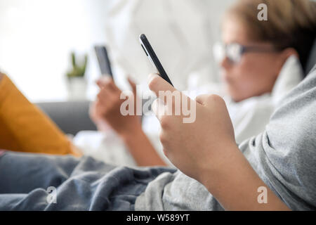 Close up photo of two boys playing with smartphones. Brothers using cell phone. Wireless technology allows to stay connected everywhere. Concept image Stock Photo