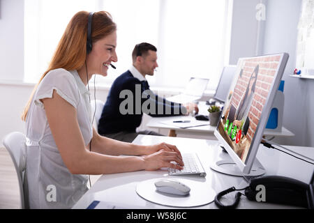 Smiling Businesswoman Wearing Headset While Video Conferencing With Her Colleague On Computer In Office Stock Photo