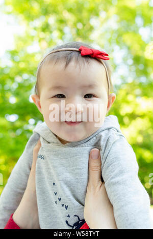 Baby girl wearing small red bow smiles and looks at camera Stock Photo