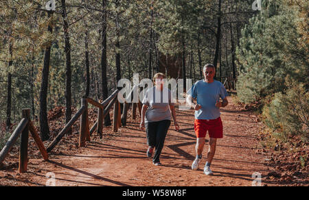 Couple active senior running outside in green nature Stock Photo