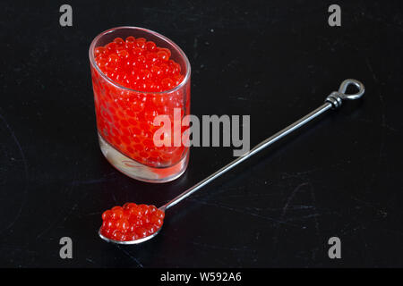 Imitation of red caviar in glass jar on black background Stock Photo