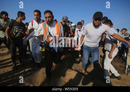 (190726) -- GAZA, July 26, 2019 (Xinhua) -- Palestinian medics carry a wounded man during clashes with Israeli troops near the Gaza-Israel border, east of southern Gaza Strip city of Khan Younis, July 26, 2019. At least 56 Palestinians were injured on Friday during clashes with Israeli soldiers in eastern Gaza Strip, close to the border with Israel, medics said. (Xinhua/Khaled Omar) Stock Photo