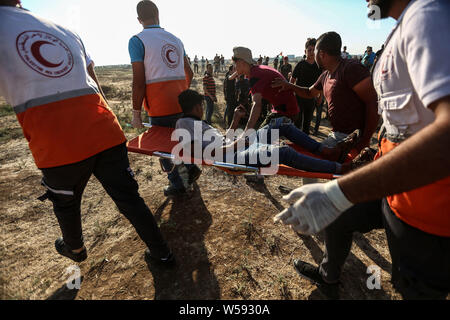 (190726) -- GAZA, July 26, 2019 (Xinhua) -- Palestinian medics carry a wounded man during clashes with Israeli troops near the Gaza-Israel border, east of Gaza City, July 26, 2019. At least 56 Palestinians were injured on Friday during clashes with Israeli soldiers in eastern Gaza Strip, close to the border with Israel, medics said. (Str/Xinhua) Stock Photo