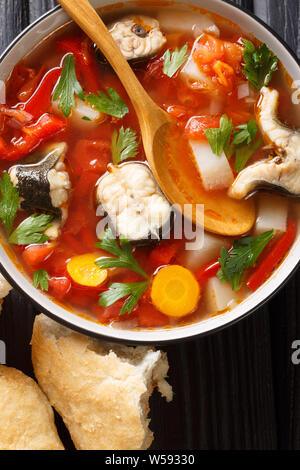Vegetable soup with eel fish and tomatoes closeup in a bowl on the table. Vertical top view from above Stock Photo