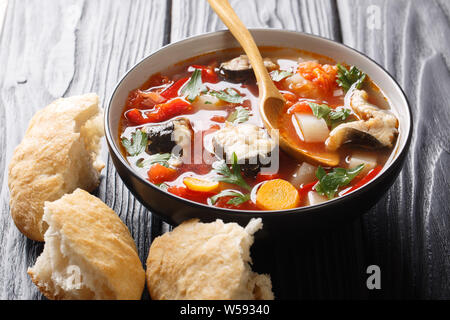 Closeup of homemade hot eel soup with tomatoes, potatoes, carrots, onions, peppers and herbs in a bowl on the table. horizontal Stock Photo