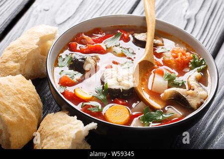 Eel soup with tomatoes, potatoes, carrots, onions, peppers and herbs closeup in a bowl on the table. horizontal Stock Photo