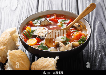 Thick tomato fish soup with eel and vegetables closeup in a bowl served with bread on the table. horizontal Stock Photo