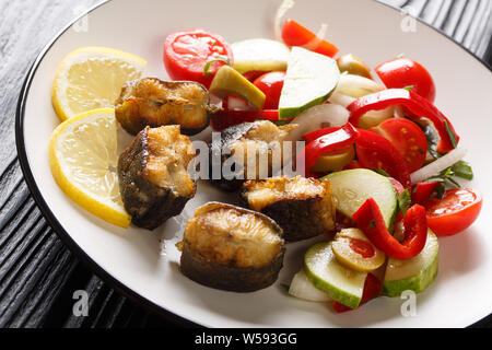 Gourmet food fried eel with fresh vegetable salad close-up on a plate on the table. Horizontal Stock Photo