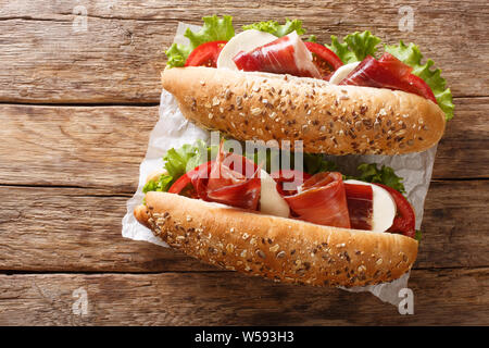 Fresh prosciutto ham sandwiches, mozzarella cheese and vegetables close-up on the table. Horizontal top view from above Stock Photo