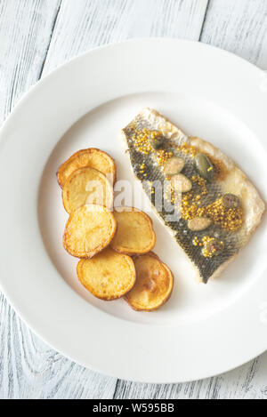 Baked sea bass with capers and fried potatoes Stock Photo