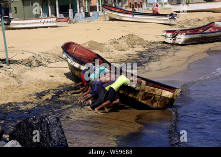 Moron, Carabobo, Venezuela. 26th July 2019. Men push a boat out into the water after an oil spill occurred in the El Palito area. The oil spill is affecting the beaches of Palma Sola in the Oron municipality of Carabobo state and Tucacas in the Morrocoy National Park of Falcon state. Credit: Juan Carlos Hernandez/ZUMA Wire/Alamy Live News Stock Photo