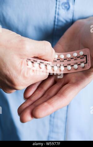 Hands holding hormone replacement therapy (HRT) pills. HRT pills are synthetic hormones used to treat menopausal women. They counteract the hormone deficiency that occurs at menopause. Stock Photo