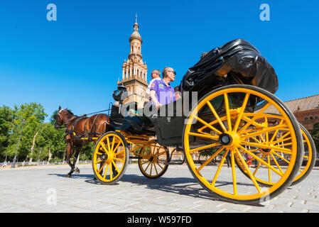 Seville, Spain - May 21, 2019: - Tourists taking a ride in a horse drawn carriage in the Plaza de Espana, Seville, Andalusia, Spain . Stock Photo