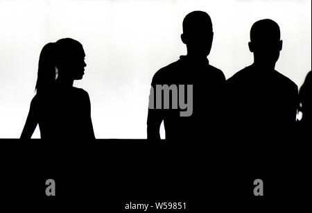 Belgrade, Serbia - July 23, 2019: Silhouettes of a teenage girl and two teenage boys walking in the night, in high contrast black and white Stock Photo