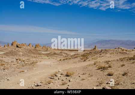 Dirt road and trails lead through brown hot dry desert hills under bright blue skies. Stock Photo