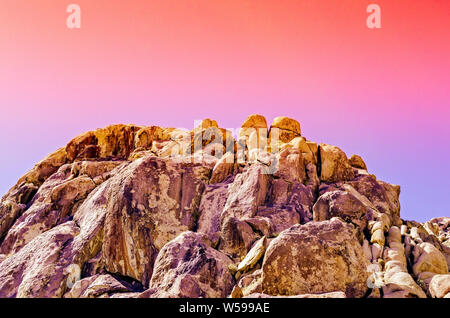 Colorful orange, pink, purple skies over desert rock formation at dusk. Stock Photo