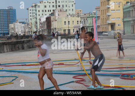 Cuban children spray water hoses - part of artwork installation on the Malecon in Havana, Cuba from the Biennial art exposition Stock Photo