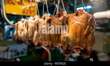 Close-up view of a stall vendor with chicken meat hanging in traditional market of Taipei. Stand with fresh chicken sold in a popular marketplace Stock Photo