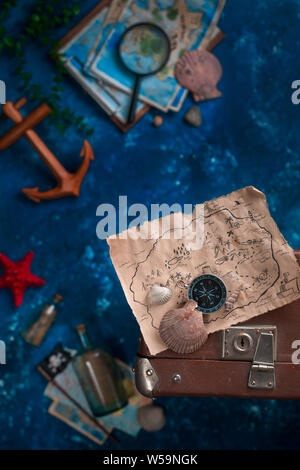 Treasure map with seashells on a suitcase. Ready to go for an adventure flat lay with copy space. Stock Photo