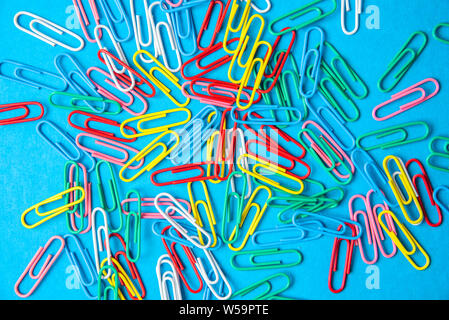 multi-colored paper clips on a blue background. Stock Photo
