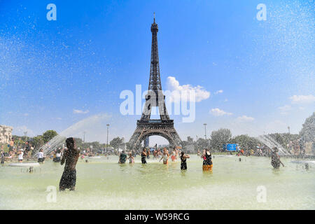 (190727) -- BEIJING, July 27, 2019 (Xinhua) -- People cool themselves at a fountain near the Eiffel Tower in Paris, France, July 25, 2019. Thursday is the hottest day of the intense heatwave episode in France's northern regions. Earlier, Meteo France forecasted that in the hottest part of the day, the temperatures under shelter will be between 40 and 42 degrees Celsius, very occasionally 43 degrees in certain districts of the capital. (Photo by Jack Chan/Xinhua) Stock Photo