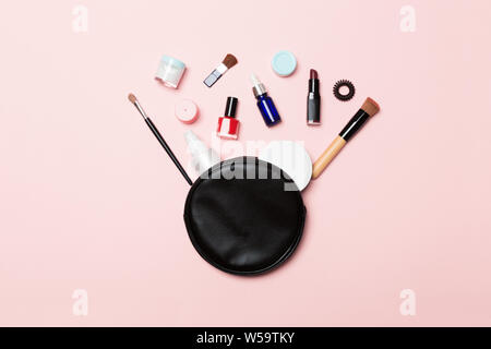Top view od cosmetics bag with spilled out make up products on pink background. Beauty concept with empty space for your design. Stock Photo