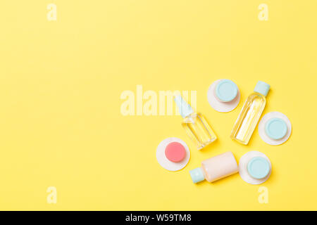 Set of travel size cosmetic bottles on yellow background. Flat lay of cream jars. Top view of bodycare style concept. Stock Photo