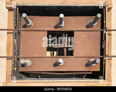 Formwork and reinforcement of concrete reinforced foundation with metal anchor bolts designed for the installation of metal columns. Top view. Stock Photo