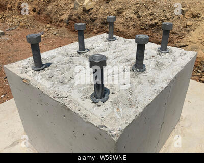 Reinforced concrete foundation with metal anchor bolts designed for the installation of metal columns. Foundation of warehouse on the construction sit Stock Photo