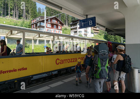 Arosa, GR / Switzerland - 24. July, 2019: tourists getting on and off the open panorama carriage of the scenic Chur - Arosa train line in the Swiss Al Stock Photo