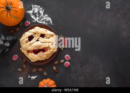 Halloween Mummy Pie, Pumpkins and Halloween Decor on dark background, top view, copy space. Homemade dessert idea for Halloween. Stock Photo