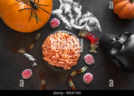 Halloween Brain mini cake, Pumpkins and Halloween Decor on dark background, top view, copy space. Homemade dessert idea for Halloween. Stock Photo