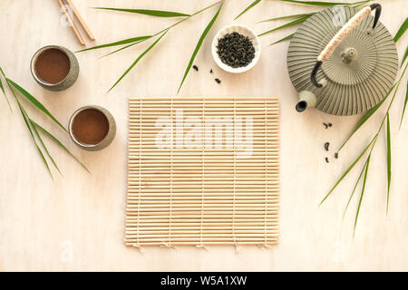 Green Tea Composition with bamboo mat and reed leaves. Chinese traditional tea set, tea culture concept, top view, copy space. Stock Photo