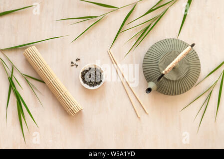 Asian food background - tea set, bowls and chopsticks with bamboo leaves on light wooden background. Asian menu design, chinese japanese cuisine conce Stock Photo