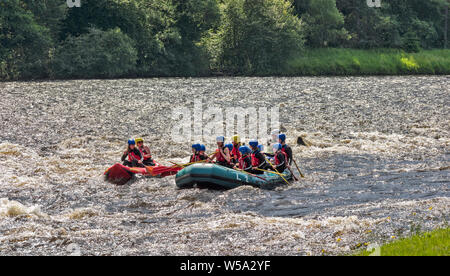 RIVER SPEY SCOTLAND PARTY OF ADULTS AND CHILDREN IN A LARGE INFLATABLE RAFT NEGOTIATING THE RAPIDS AND A SMALLER RED RAFT ALONGSIDE Stock Photo
