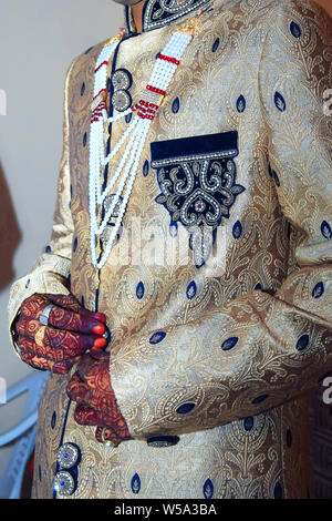 Strong handsome Indian groom holds his hands over wedding suit Stock Photo
