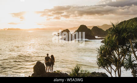 Couple enjoying sunset with amazing ocean and mountain view. Travel concept, panoramic shot, wanderlust. Stock Photo
